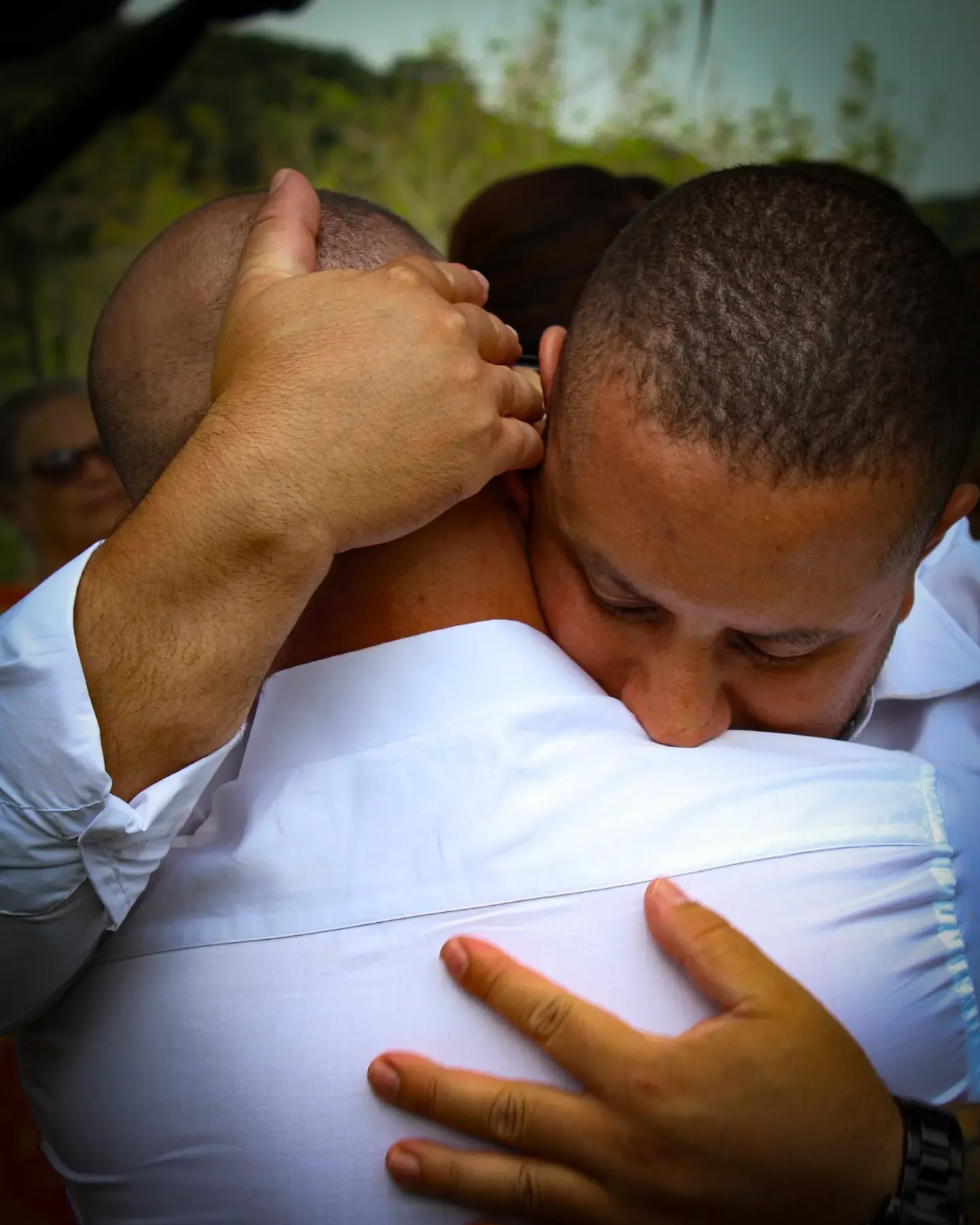 Dois homens se abraçam de olhos fechados.