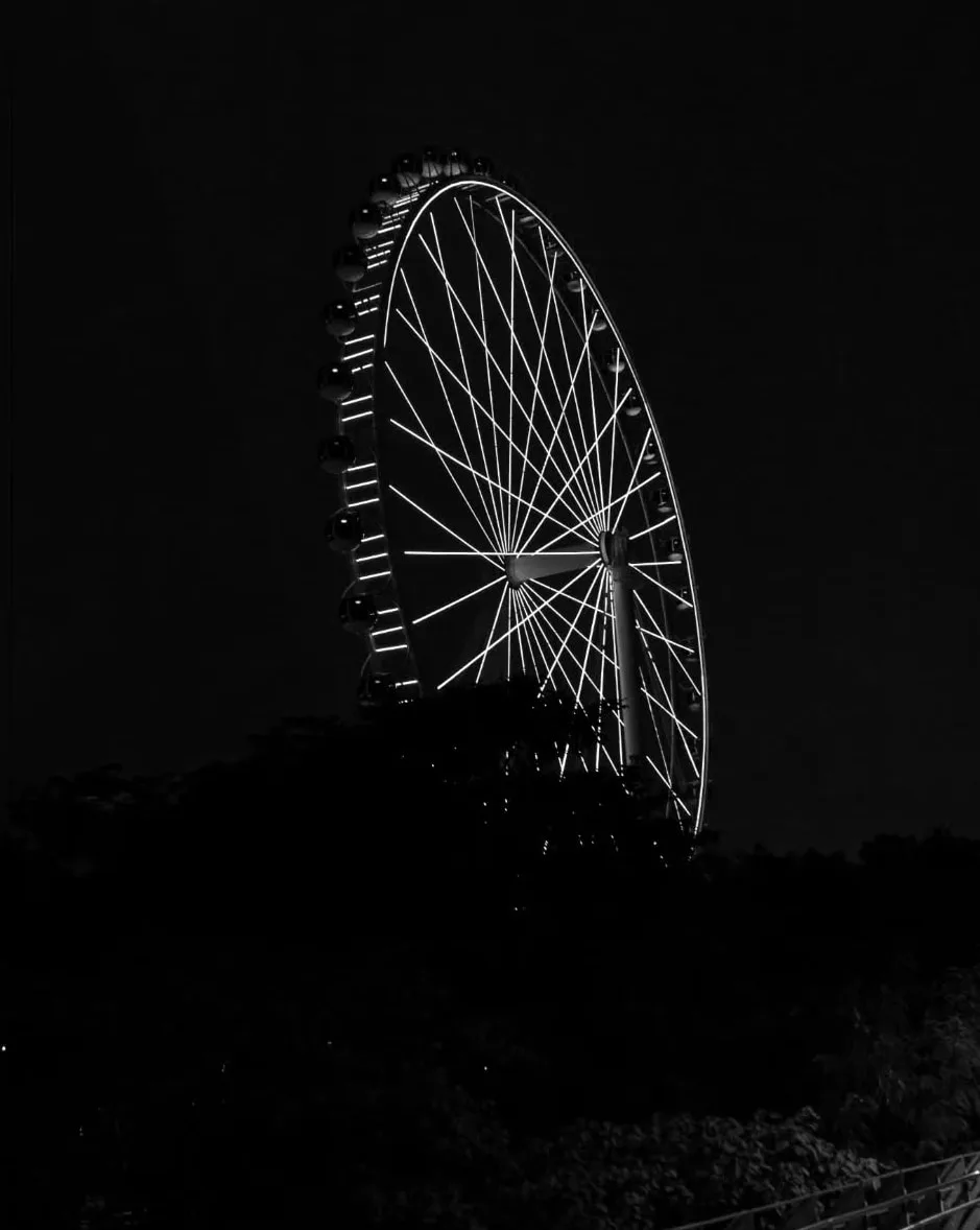 Silhueta da roda-gigante em linhas brancas sobre fundo preto.
